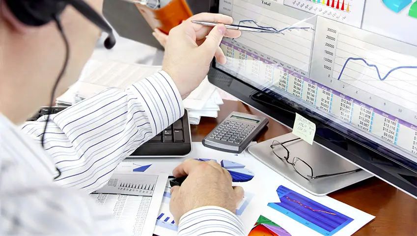 Financial adviser pointing with a pen at a chart on a computer screen