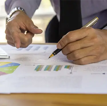 Financial adviser pointing at charts and graphs while writing