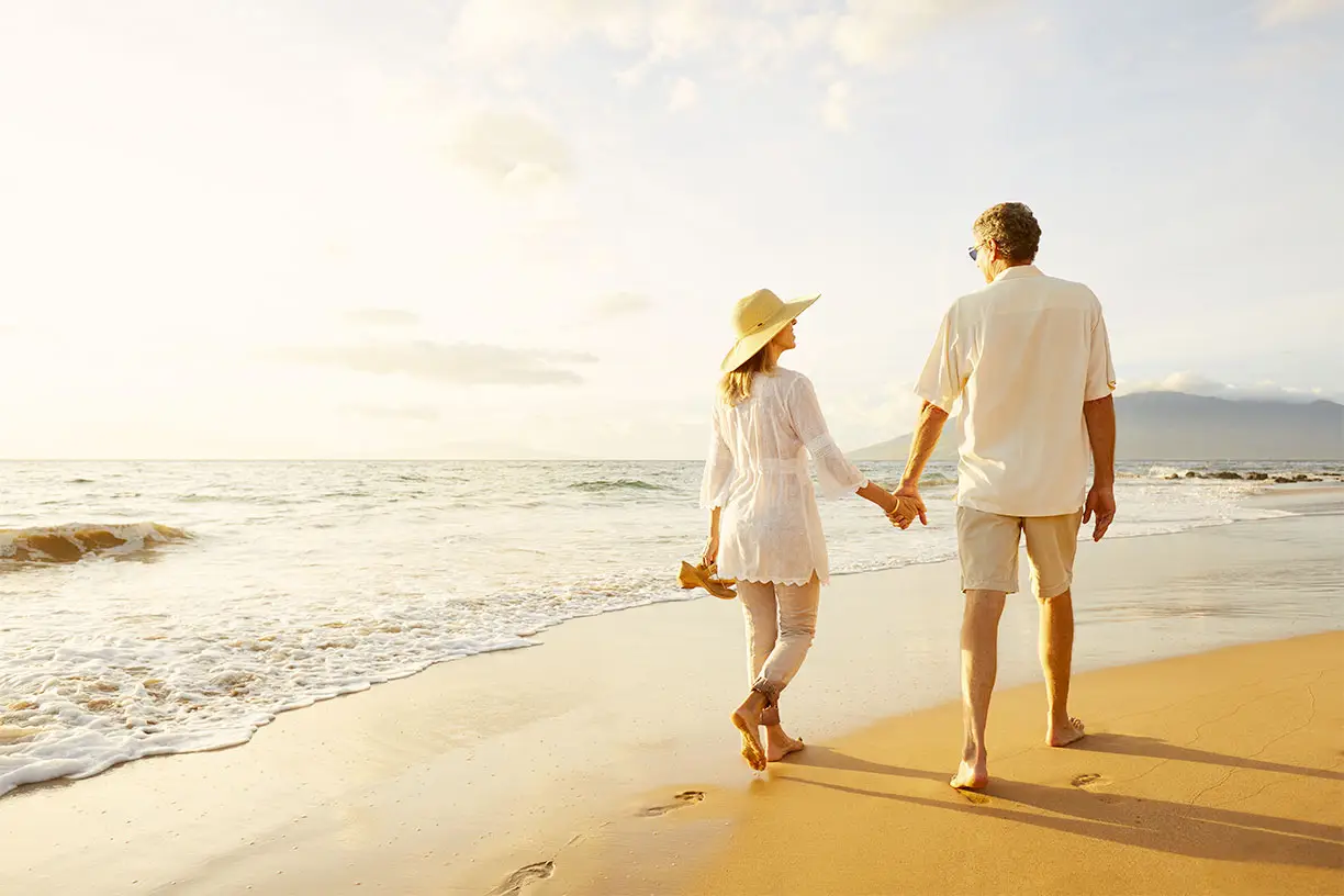 couple walking on beach while holding hands